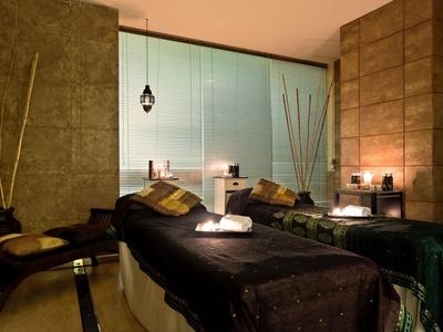 Gemütlicher Wellnessraum mit zwei Massageliegen, gedämpfter Beleuchtung und entspannender Atmosphäre.