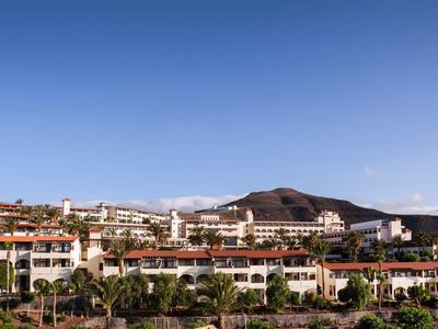 Hotel complex with terracotta roofs and balconies under a clear blue sky.
