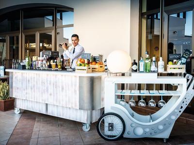 Bartender mixing drinks at a stylish outdoor bar with various bottles and glassware.