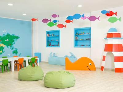 Colorful kids' playroom with bean bags, small chairs, fish wall decals, and a lighthouse structure.