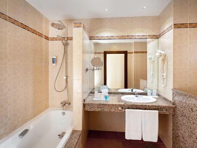 Bathroom with bathtub, shower, mirror, sink, and towels in a hotel setting.