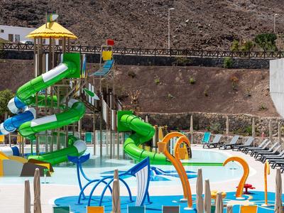 Colorful outdoor water park with slides and splash features in a sunny, arid landscape.