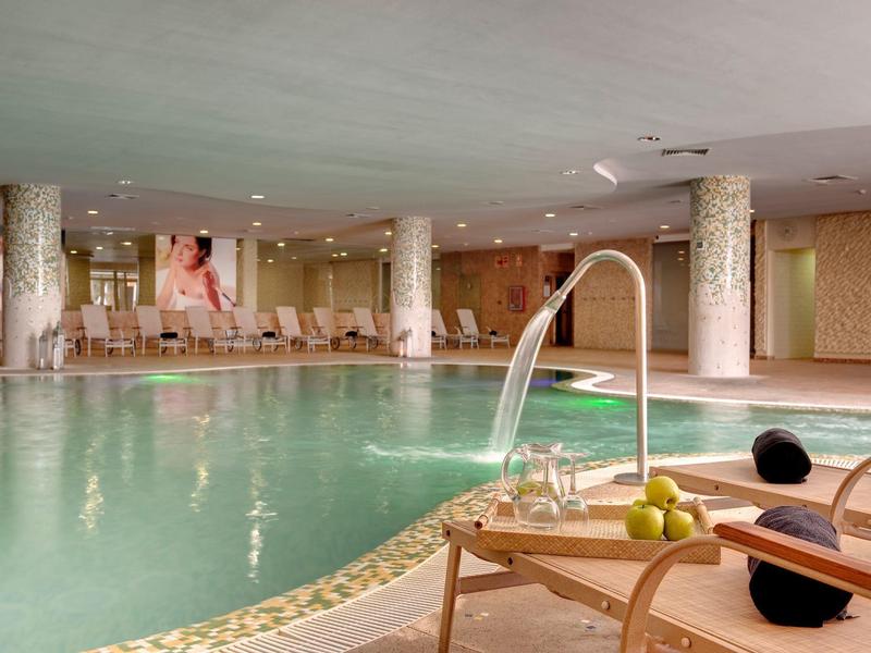 Indoor pool area with water jets, lounge chairs, and a relaxed ambiance in warm lighting.