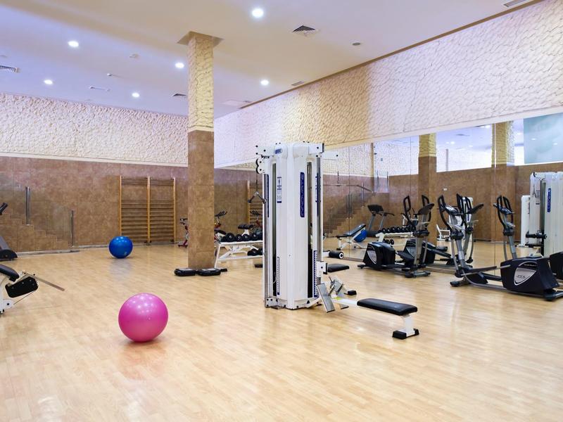 Spacious gym with exercise machines, stability balls, and mirrors on the wall.