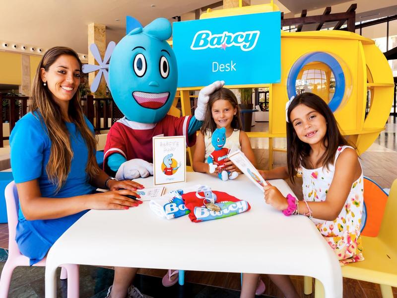 Children and a staff member enjoying crafts at a colorful hotel kids' activity desk.