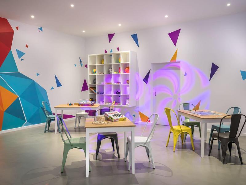 Modern dining area with colorful chairs, geometric wall art, and minimalist décor.