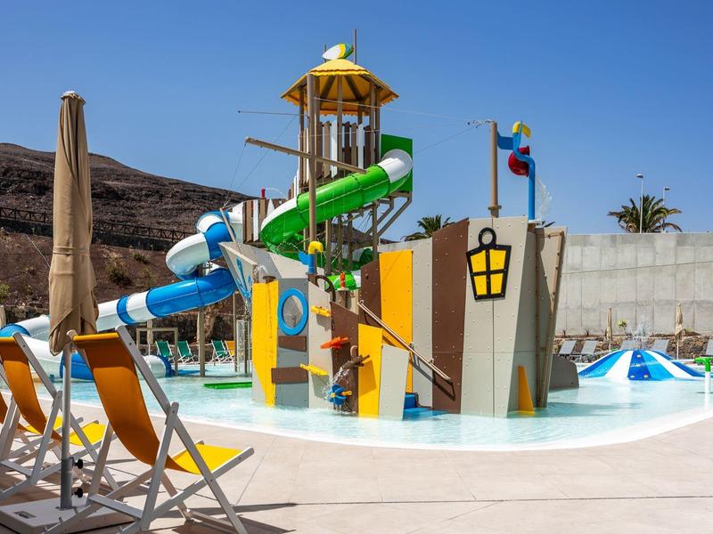 Outdoor colorful water play area with slides and pool under clear blue sky.