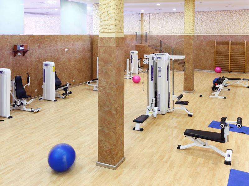 Spacious gym with wooden floors, exercise machines, and fitness balls in a hotel setting.