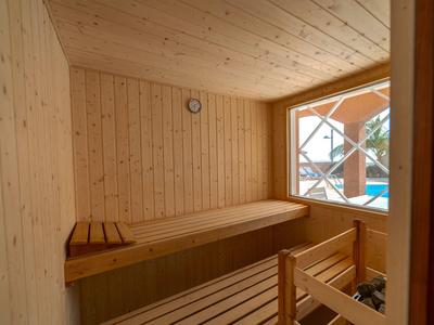 Kleine Holzsauna mit Holzbänken, Fenster und warmer Beleuchtung.