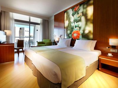 Chambre d'hôtel moderne avec grand lit double, sol en bois et décoration murale colorée.