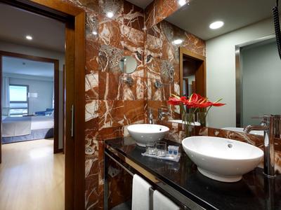 Nowoczesna łazienka z podwójną umywalką i czerwonymi kwiatami na czarnym blacie.