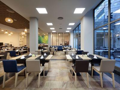 Nowoczesna jadalnia z stołami, krzesłami i dużymi oknami w hotelu.