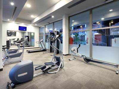 Sala de fitness moderna con equipo cardiovascular y grandes ventanas en un hotel.