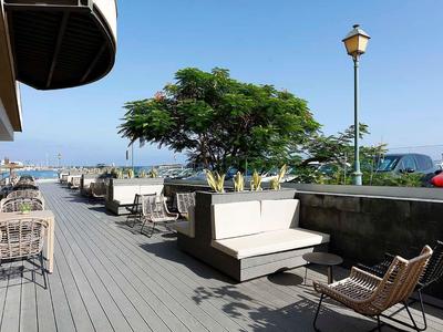 Zewnętrzny taras z miejscami do siedzenia i widokiem na morze pod bezchmurnym niebem.