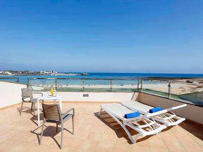 Terraza con dos tumbonas y una mesa con sillas con vistas al mar.