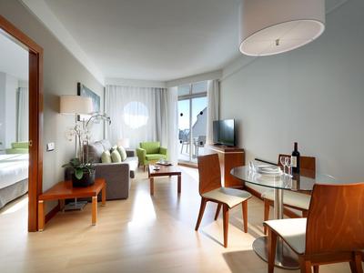 Suite d'hôtel moderne avec salon, coin repas et vue sur le lit.