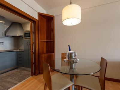 Un coin repas avec une table ronde en verre, trois chaises et une porte menant à la cuisine en arrière-plan.