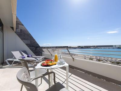 Balcon avec table, chaises, chaises longues, vue sur la mer et ciel bleu.