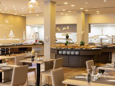 Jasna i nowoczesna restauracja hotelowa z nakrytymi stołami i stanowiskami bufetu.