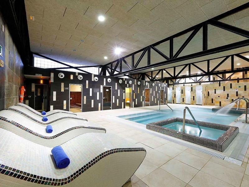 Nowoczesna wewnętrzna strefa basenowa z jacuzzi i leżakami w hotelu.