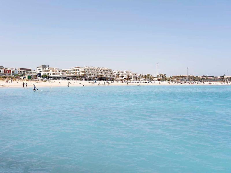 Plaża z czystą, niebieską wodą i budynkami w tle w słoneczny dzień