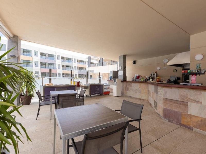 Zadaszony taras z stołami, krzesłami i barem w nowoczesnym hotelu.