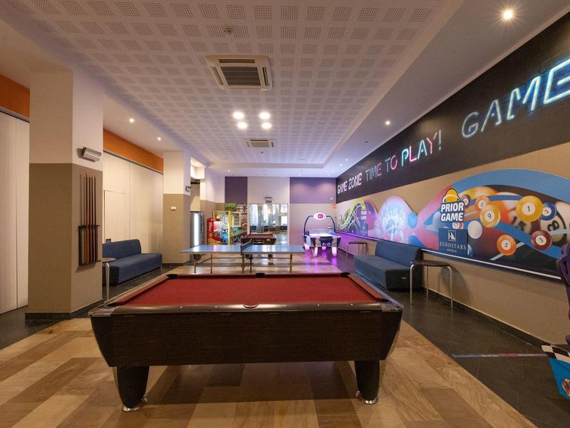 Pokój gier z bilardem, automatami do gier i miejscami do siedzenia w hotelu.