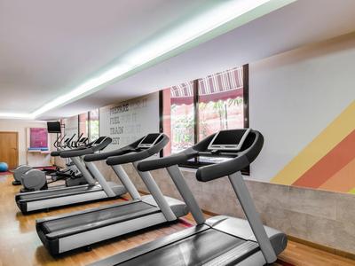Moderner Fitnessraum mit mehreren Laufbändern, Holzboden und heller Wandgestaltung mit Streifen.