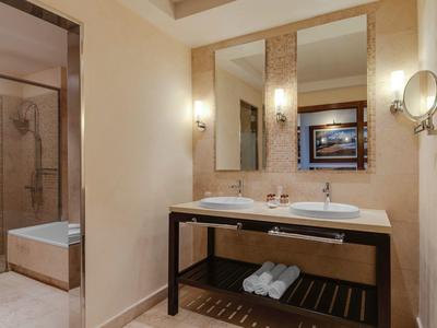 Elegantes Badezimmer mit Doppelwaschbecken, großem Spiegel, Handtüchern und begehbarer Dusche.