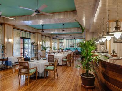 Helles, gemütliches Hotelrestaurant mit Holzboden, runden Tischen und Deckenventilatoren.