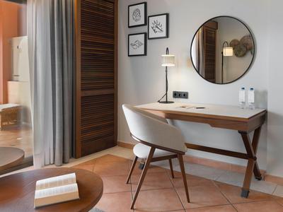 Moderner Arbeitsbereich mit Stuhl, Schreibtisch und rundem Spiegel in einer Hotelunterkunft.