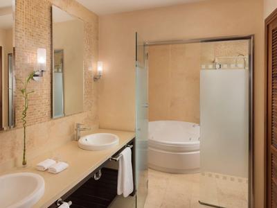 Modernes Hotelbad mit Doppelwaschbecken, freistehender Badewanne und Duschkabine in Beige.