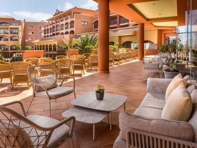 Gemütliche Terrasse mit Sitzgruppen und Blick auf Hotelgebäude und Garten.