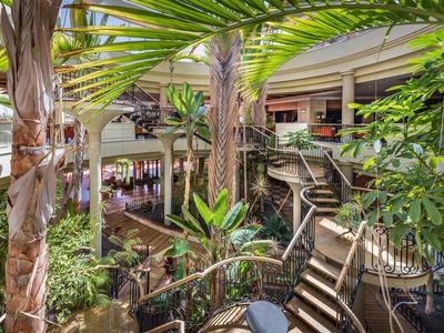 Grüne tropische Pflanzen und Palmen im Innenhof eines Hotels mit Treppen und Sitzbereichen.