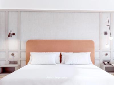 Ein modernes Hotelzimmer mit einem großen Doppelbett und minimalistischem Design.