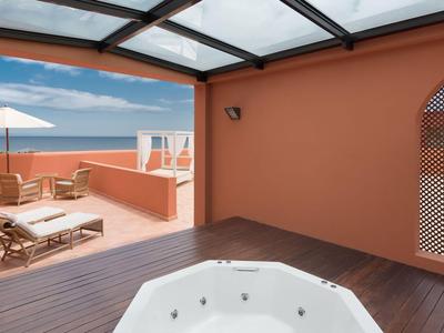Moderner Dachterrassenbereich mit Whirlpool, Sonnenliegen und Meerblick.