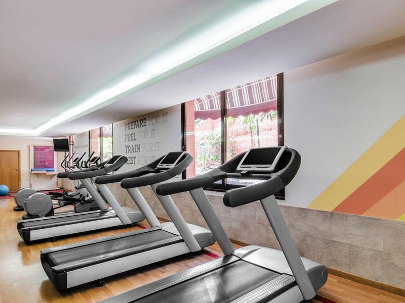 Moderne loopbanden in een goed verlichte fitnessruimte met kleurrijke wanddecoratie.