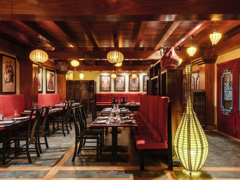 Elegant restaurant met houten plafond, rode zitplaatsen en warme verlichting.