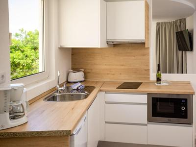 Moderne Küche mit Holzarbeitsplatten, weißem Schrankdesign und eingebautem Backofen.