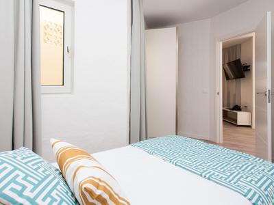 Kleines Schlafzimmer mit blau gemusterten Betten, offenem Fenster und Blick ins Wohnzimmer.