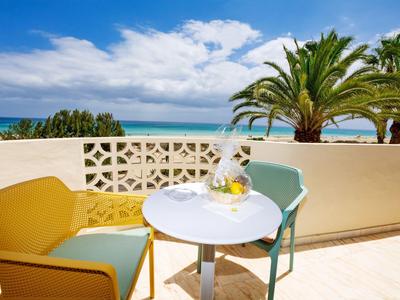 Zithoek met kleurrijke stoelen en uitzicht op palmbomen en de zee