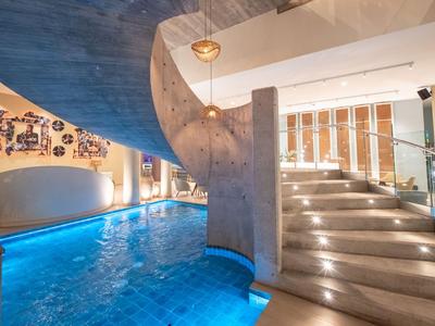 Moderner Hotelinnenpool mit gewundenem Treppenaufgang und entspannter Atmosphäre.