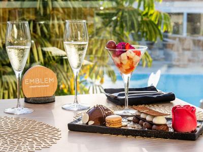 Tisch mit Sektgläsern, Dessert und Schokolade neben einem Pool in tropischer Umgebung.