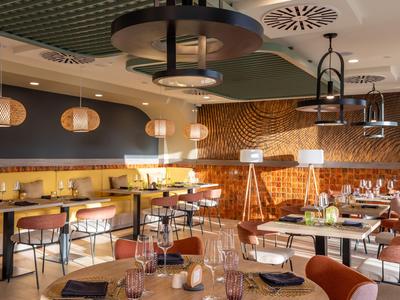Modernes Restaurant mit warmem Holzdekor, bequemen Stühlen und stilvollen Beleuchtungselementen.