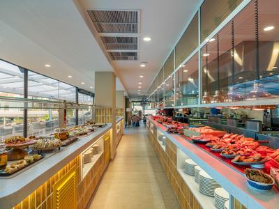 Modernes Hotelbuffet mit vielfältigen Speisen an langen Tischen und heller Beleuchtung.