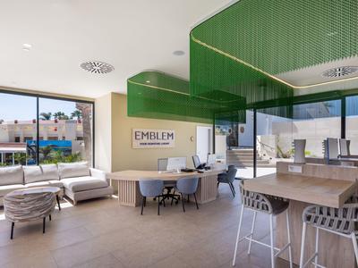 Modernes Hotelinnendesign mit grünen Deckenpaneelen, großen Fenstern und stilvollen Sitzbereichen.