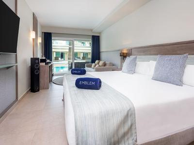 Modernes Hotelzimmer mit Doppelbett, TV, Sitzbereich und Blick auf Balkon.