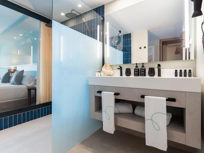 Moderner Hotelbadezimmerbereich mit grauem Waschbecken und Badetüchern.