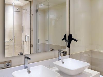 Modern hotel bathroom with two square sinks, large mirror, and glass shower enclosure.