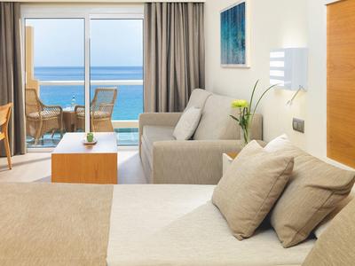 Modern hotel room with balcony, sea view, and cozy interior in light colors.